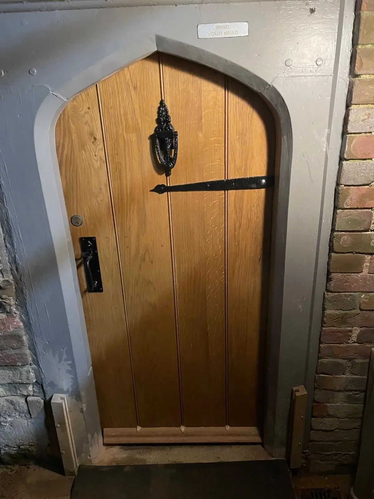 Arched oak ledged door with wrought-iron strap hinges and knocker in a brick and stone doorway