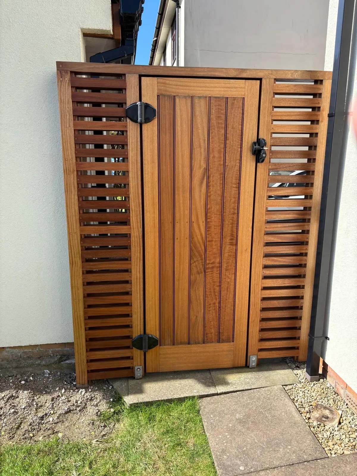Hardwood side gate with matching slatted screen panels and keypad lock against a rendered wall
