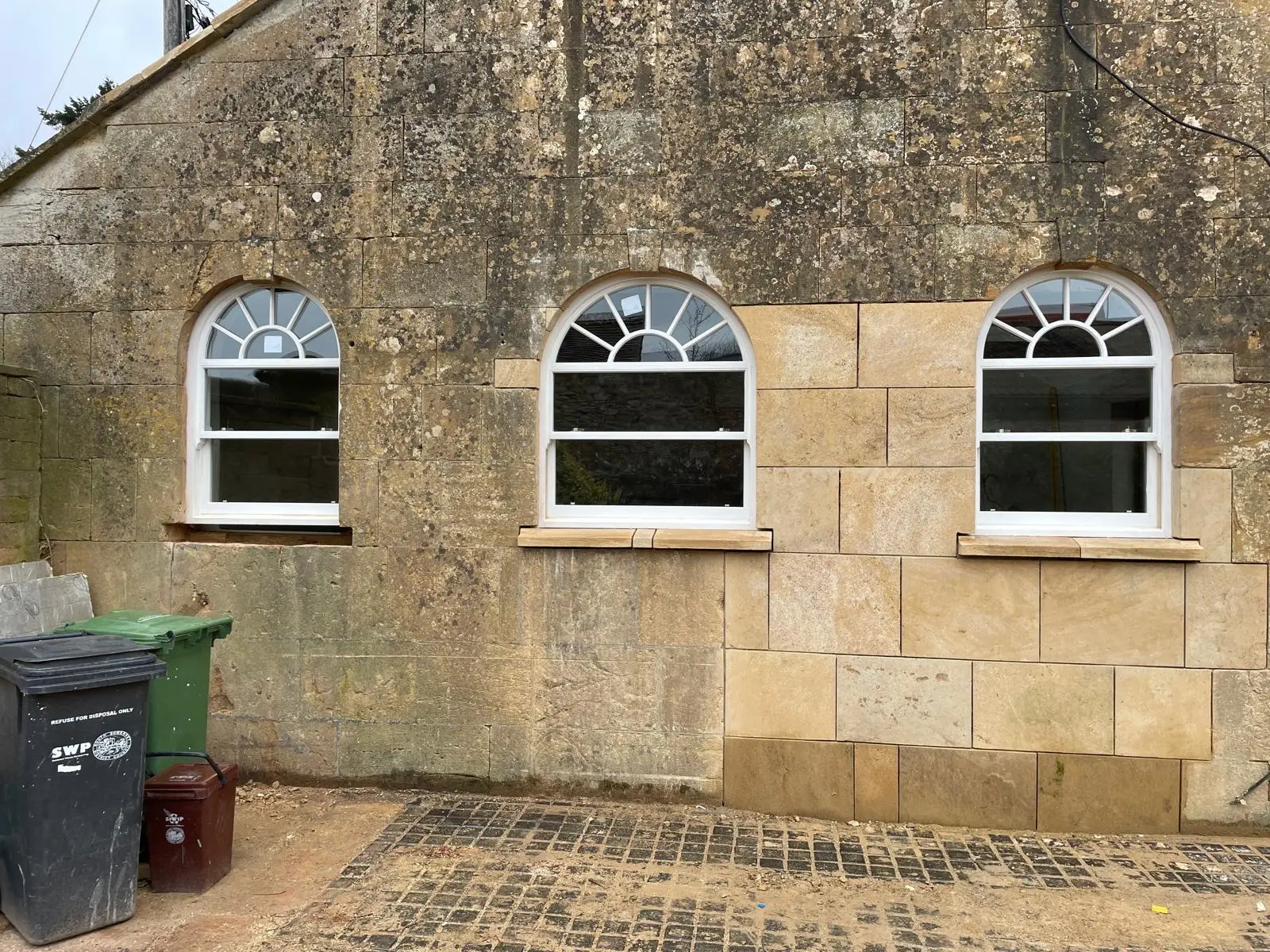 Three arched timber sash windows with radial glazing bars in a Dorset stone building