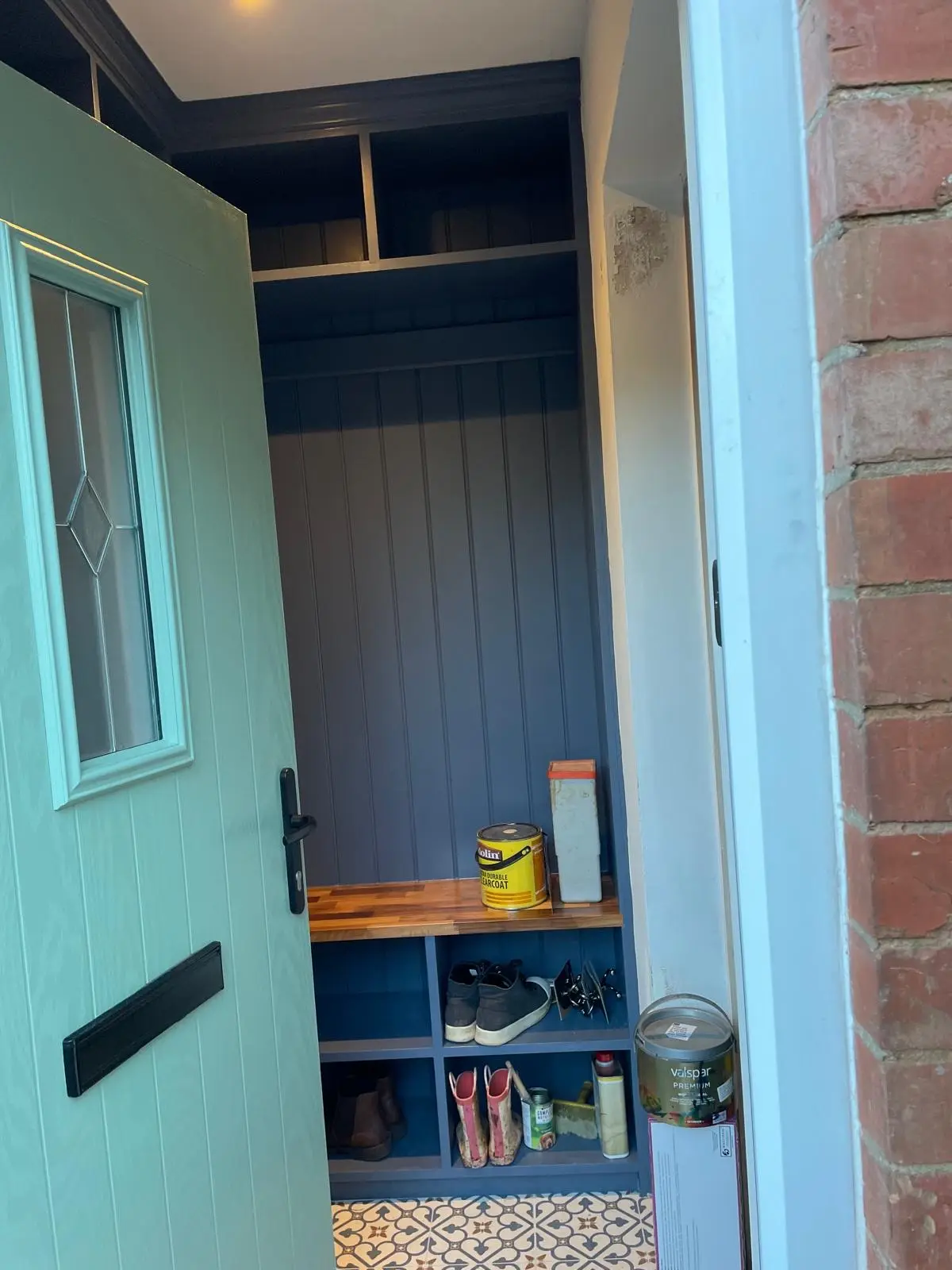 Bespoke fitted boot room with tongue-and-groove panelling, oak bench seat and cubby shelving in deep blue