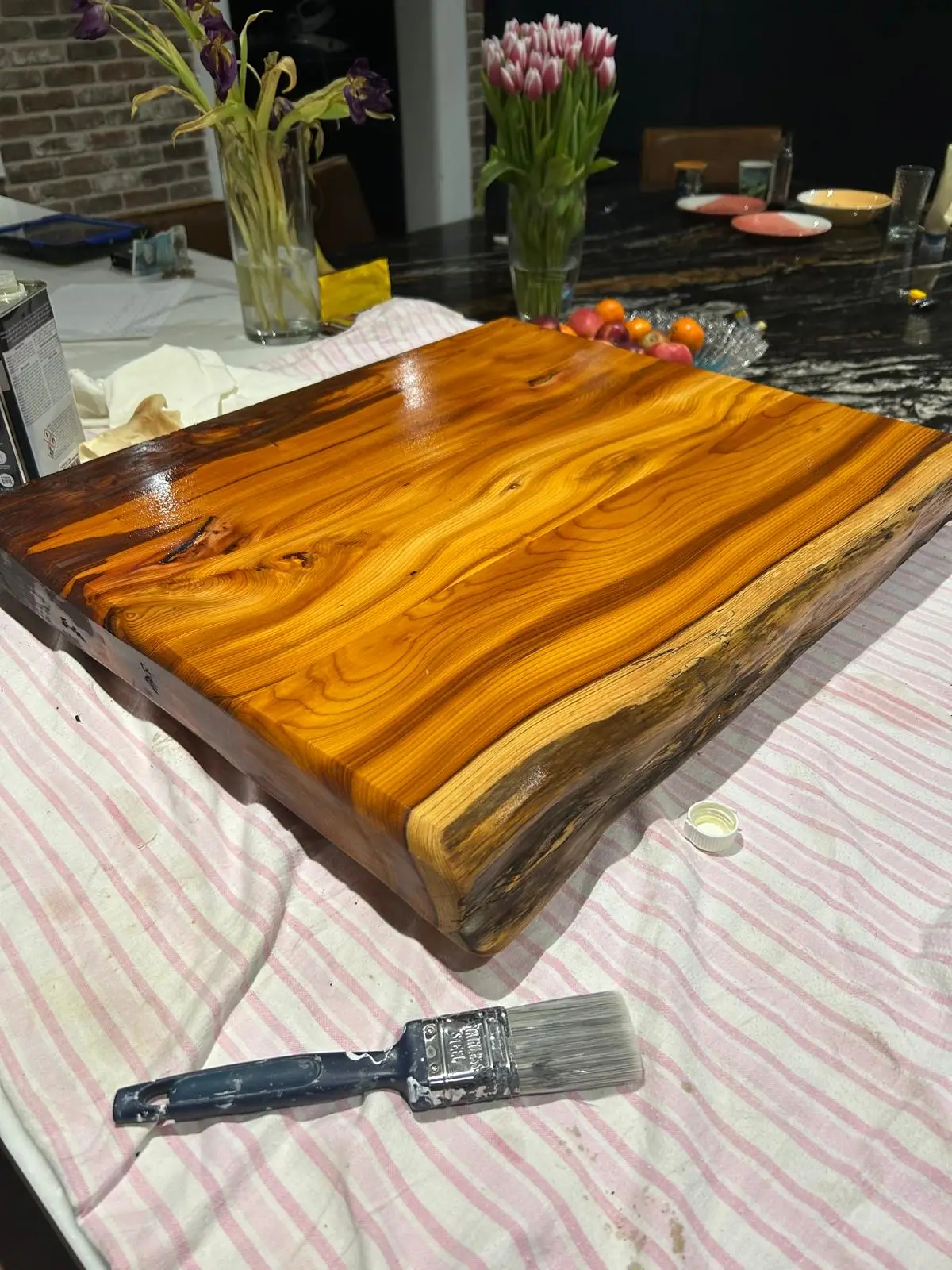 Live-edge yew board with a glossy oiled finish, showing the natural waney edge
