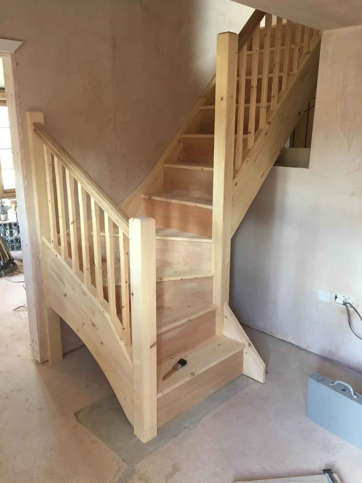 Complete pine staircase with balustrade, spindles and a curved skirt panel in a plastered room