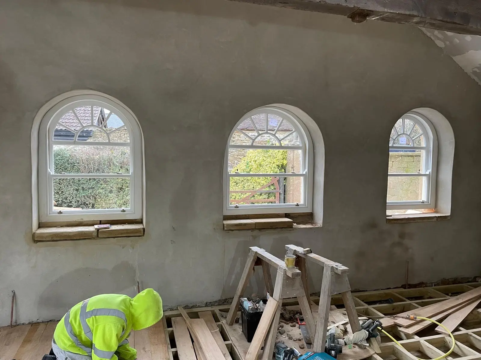 Arched timber sash windows with fanlight glazing seen from inside a curved plastered wall