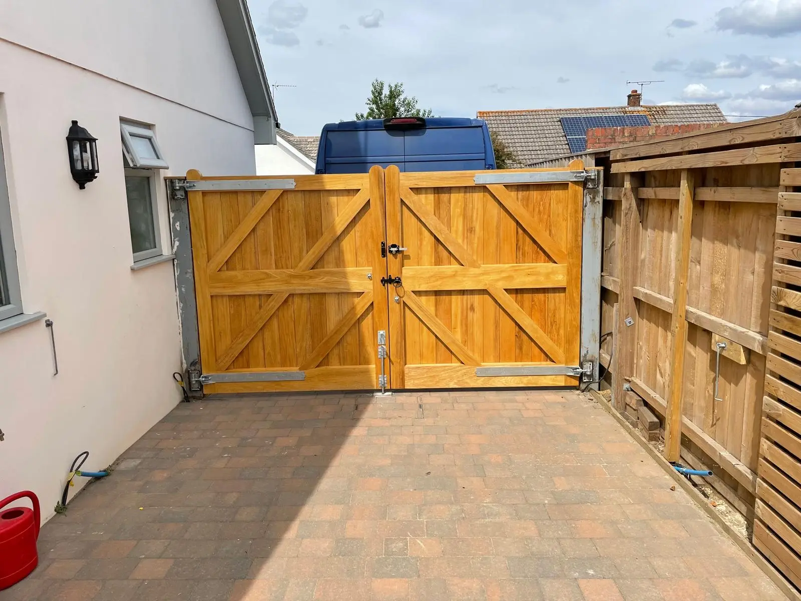 Oak driveway gates with twin locks viewed from a block-paved courtyard