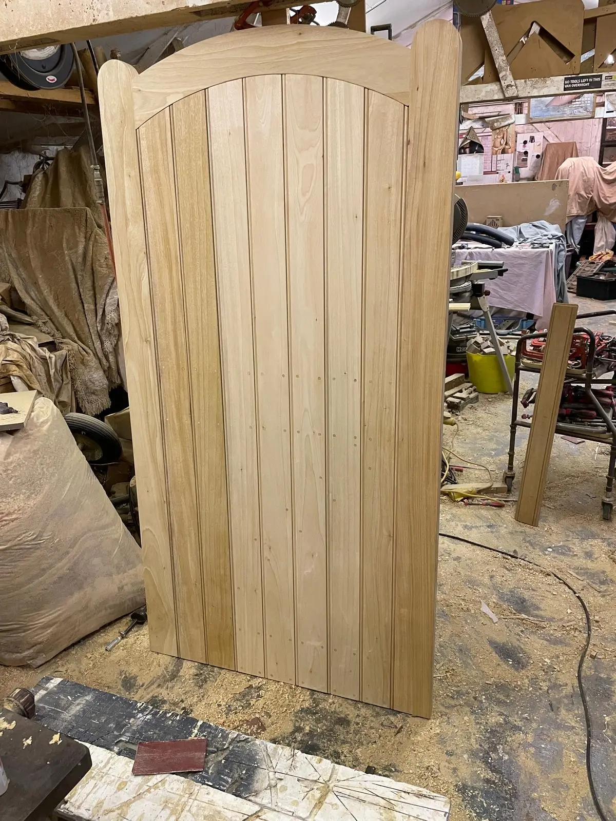 Bespoke curved-top tongue-and-groove timber garden gate, newly made in the workshop