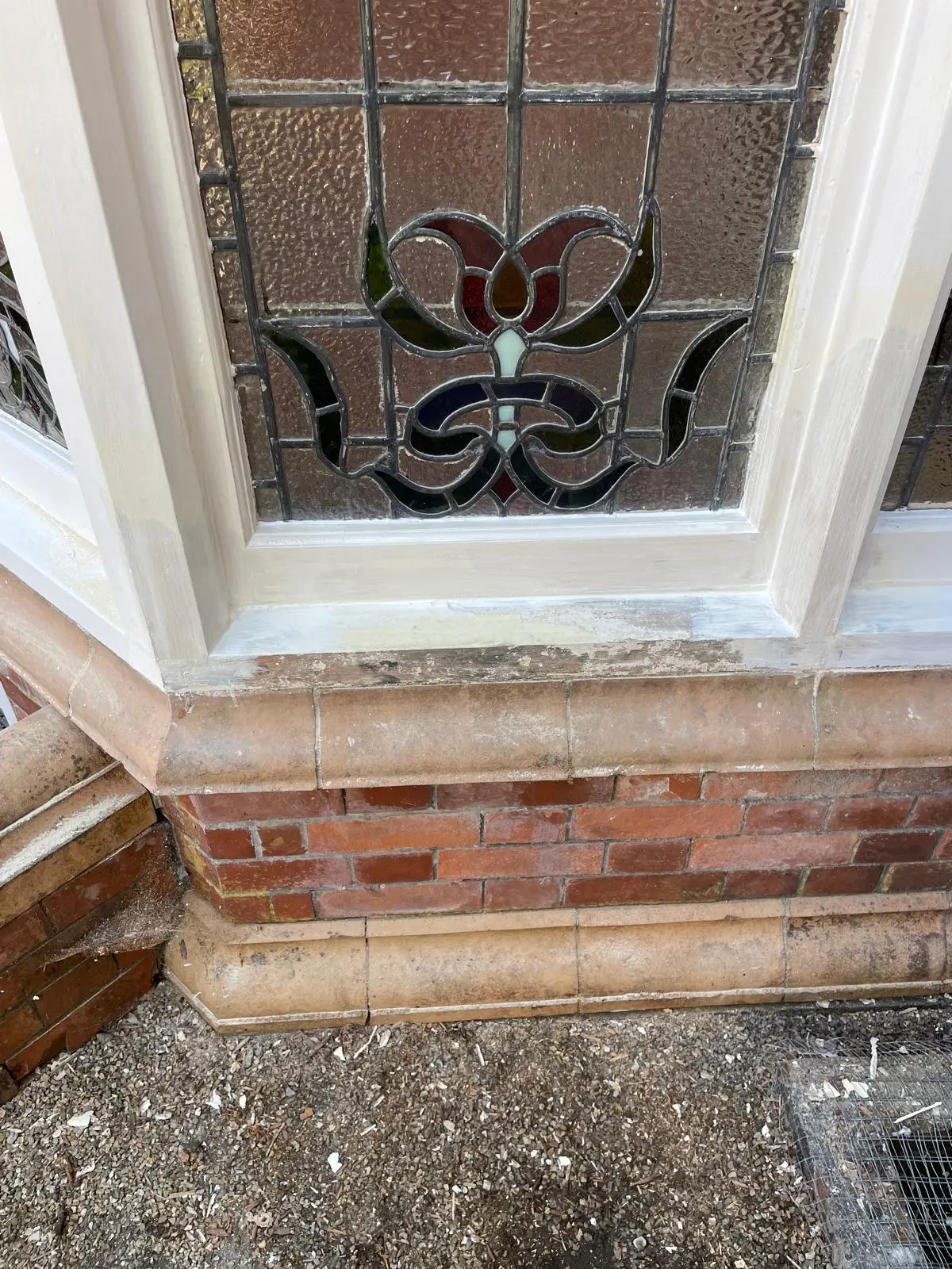 Restored leaded stained-glass window with repointed brick bay and renewed painted timber cill